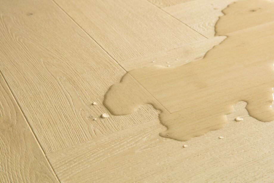 kalanruoto-laminaatti-quick-step-impressive-design-ginger-oak Kalanruoto laminaatti Quick Step Impressive Design Ginger Oak, lämmin keskiruskea tammen sävy ja tasainen lajitelma, vesilätäkkö osoittamassa vedenkestävyyttä