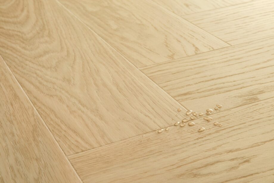 Vinüülparkett kalasaba Quick-Step Ciro Pure Oak Blush tooni ja disaini kirjeldus veepiiskadega põrandal viitamaks veekindlusele