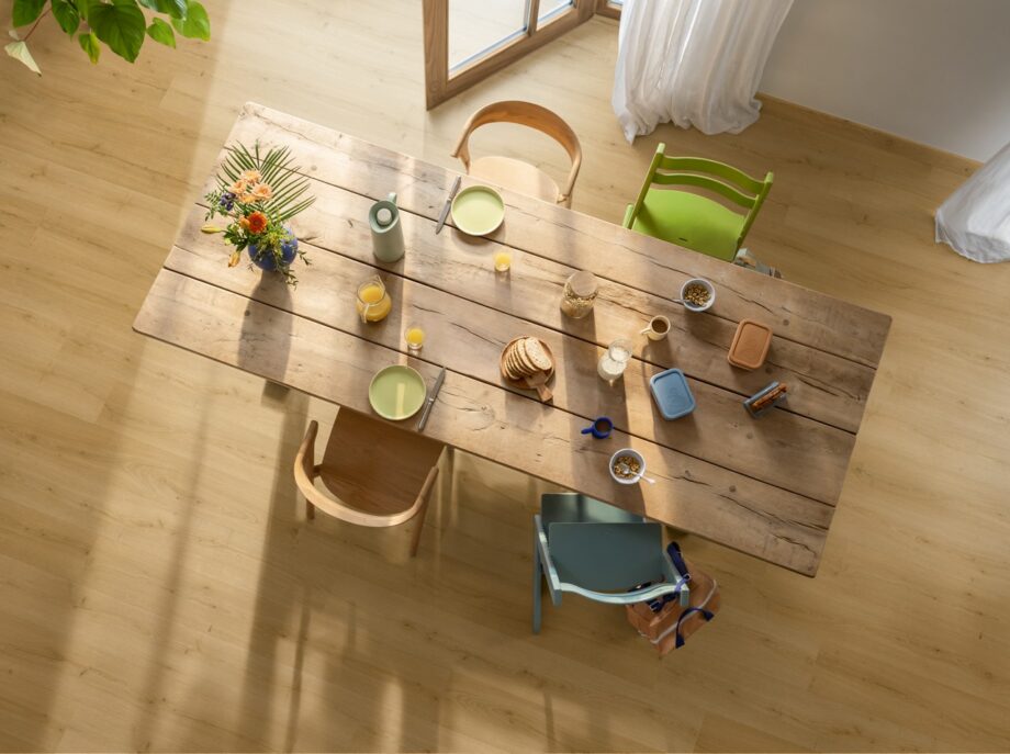 LVT Floors Quick Step Bloom Brushed Oak Honey installed on a dining room floor. Dining table with breakfast and flowers.