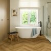 herringbone-laminate-floor-quick-step-impressive-design-cinnamon-oak Herringbone laminate floor Quick-Step Impressive Design Cinnamon installed to bathroom floor. White separatly standind bathtub