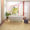 laminat-fischgrat-quick-step-impressive-design-ginger-oak Laminat Fischgrät Quick Step Impressive Design Ginger Oak, verlegt im Badezimmerboden, freistehende weiße Badewanne, mit blauer Mosaikfliese verkleideter Sockel und rote Fensterrahmen