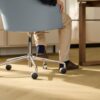 laminat-quick-step-impressive-design-nutmeg-oak Laminat Quick Step Impressive Design Nutmeg Oak, verlegt im Büro, blauer Bürostuhl mit sitzendem Mann