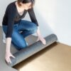 underlay-for-parquet-and-laminate-quick-step-pergo-silentwalk Woman is rolling the Quick-Step SilentWalk parquet and laminate floor underlay roll open on the underfloor