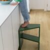 klick-vinyl-quick-step-bloom-botanic-beige Klick Vinylboden Quick Step Bloom Botanic Beige in der Küche verlegt, ein Kind steht auf einem Stuhl und nimmt eine Orange aus einer Obstschale auf der Kücheninsel.