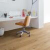 LVT floor Quick-Step Bloom Cotton Oak Natural installed on a home office floor. White office table, brown leather office stool and a lamp.