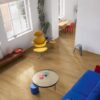 lvt-flooring-quick-step-bloom-cotton-oak-deep-natural LVT flooring Quick-Step Bloom Cotton Oak Deep Natural installed on a livingroom floor. Blue sofa, sofa table, yellow chair.