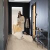lvt-porand-quick-step-bloom-sea-breeze-oak-beige LVT põrand Quick-Step Bloom Sea Breeze Oak Beige paigaldatud koridori põrandale. Naine sisenes tuppa märja vihmavarjuga.