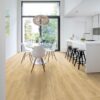 LVT põrandakate Quick-Step Blos Drift tamm beige paigaldatud köögi põrandale. Valge köögimööbel, köögisaar koos musta värvi toolidega. Ümar söögilaud koos valgete toolidega.
