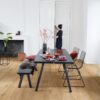 Vinüülparkett Quick-Step Bloom Cotton Oak Natural paigaldatud söögitoa põrandale. Söögilaud koos toolidega, kamina, naine võtab kapist midagi.