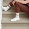 Vinüülparkett Quick-Step Blos Chia tamm helehalli tooniga paigaldatud koridori põrandale ja trepile. Mees istub trepil ja vaatab telefoni.