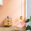 виниловыи-ламинат-quick-step-bloom-botanic-beige Виниловый ламинат Quick Step Bloom Botanic Beige уложен на полу в коридоре, розовый стул, комод и лампа, женщина моет пол шваброй.