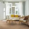 Tammeparkett Bauwerk Boen Casapark tamm 46 Vivo haratud Avorio hele õlivaha paigaldatud elutoa põrandale. Valge diivan erinevat värvi patjadega. Eriti suur valge põrandalamp, puidust punutud tugidool valge pehmendusega, diivanilaud.