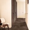 Vinyl flooring tiles Quick-Step Oro Cinnamon rock with dark brown bevelled natural stone flooring design. Installed on a hallway floor. Cow leather stool, integrated hallway closet.