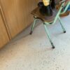 кварц-винил-quick-step-illume-pebble-concrete Кварц-винил Quick-Step Illume Pebble Concrete уложен на полу кухни — ребёнок стоит на старом стиле стуле, рядом стоит отец; светлый бетонный оттенок и спокойный бетонный дизайн.