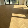 Bauwerk Monopark Oak Natur 15 Avorio herringbone parquet in a spacious room Herringbone parquet Bauwerk Monopark Oak Natur 15 Avorio in a spacious bright room with large windows