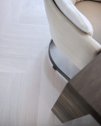 Herringbone parquet Bauwerk Monopark Oak Natur 15 Farina B-Protect® white matt lacquer – close-up of the light oak floor under a chair and table